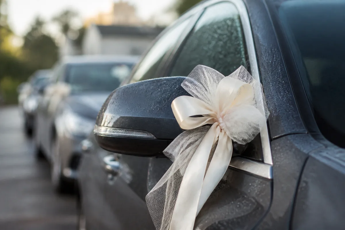 Rubans et nœuds de tulle noués sur le rétroviseur d’une voiture d’invité